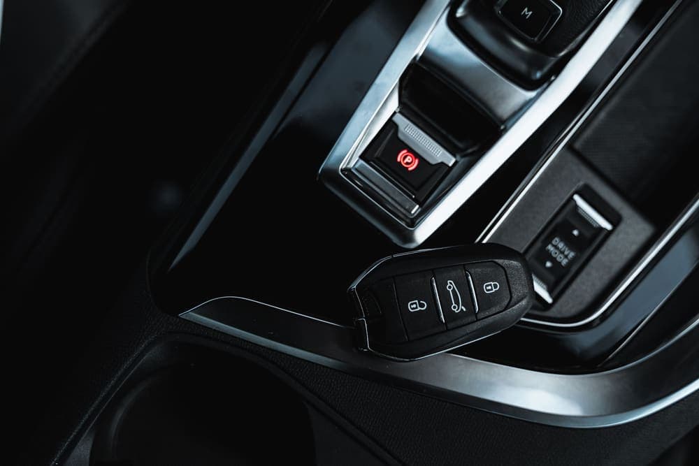 Keyless key fob beside a car's electronic handbrake