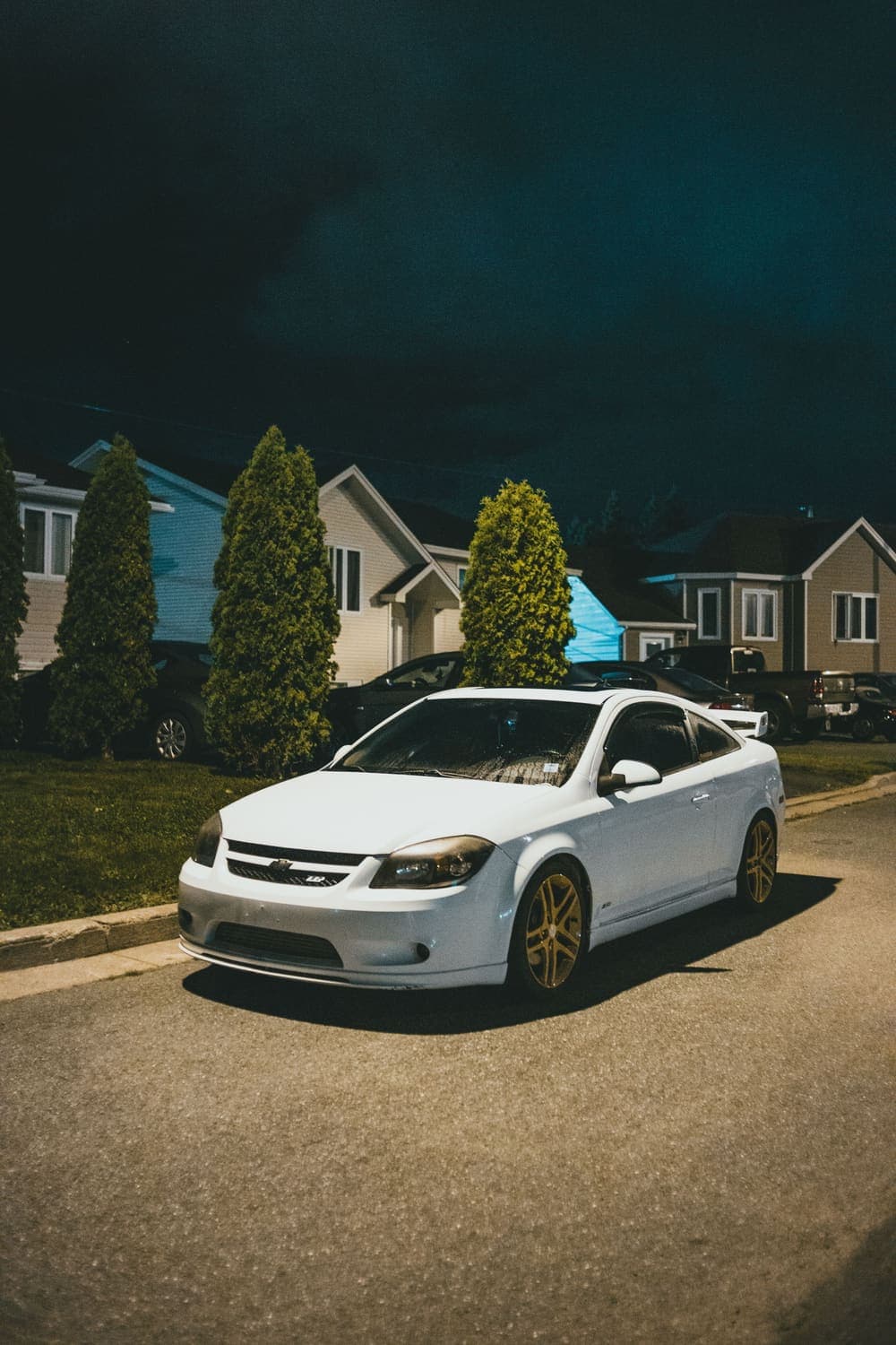 White car parked on a residential street at night